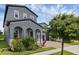 Gray two-story home showcasing arched entryway, brick driveway, and lush landscaping at 14513 Winter Stay Dr, Winter Garden, FL 34787