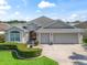 Charming single-story home boasts a three-car garage, lush landscaping, and a welcoming front entrance at 1642 Pennecamp Dr, The Villages, FL 32162