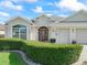 Beautiful single-story home with manicured hedges, an entryway with accent lighting, and a three-car garage at 1642 Pennecamp Dr, The Villages, FL 32162