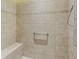 Walk-in shower with tiled walls, safety bar, and built-in bench, offering a comfortable and accessible experience at 1642 Pennecamp Dr, The Villages, FL 32162