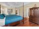 Spacious main bedroom with hardwood floors, ceiling fan, and a four-post bed with access to the ensuite and walk-in closet at 1642 Pennecamp Dr, The Villages, FL 32162