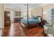 Main bedroom with hardwood floors, a ceiling fan, and a four-post bed with an ensuite bathroom at 1642 Pennecamp Dr, The Villages, FL 32162