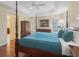 Bright main bedroom with hardwood flooring, ceiling fan, and a four-post bed complemented by soft, natural light at 1642 Pennecamp Dr, The Villages, FL 32162