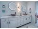 Stylish bathroom featuring double sinks, round backlit mirrors, and a modern vanity with marble countertop at 17563 Se 122Nd Ter, Summerfield, FL 34491