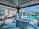 Covered patio with modern grill, comfortable seating area, and serene pool views at 17563 Se 122Nd Ter, Summerfield, FL 34491