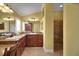 Bathroom features a granite countertop, wood cabinets, and a tiled shower with seat and grab bar at 1828 Hollow Branch Way, The Villages, FL 32162