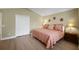Bright bedroom featuring a queen size bed, an ensuite closet, and warm interior paint at 1828 Hollow Branch Way, The Villages, FL 32162