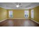 Spacious bedroom with ceiling fan, wood flooring, and bright windows with shutters at 1828 Hollow Branch Way, The Villages, FL 32162
