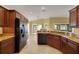 Kitchen showing stainless steel appliances, wood cabinets, granite counters, and tile flooring at 1828 Hollow Branch Way, The Villages, FL 32162