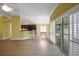 Bright living room featuring wood floors, sliding glass doors, and views into the kitchen and dining area at 1828 Hollow Branch Way, The Villages, FL 32162