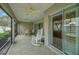 Covered screened-in patio with rocking chairs offers serene views of the backyard at 1828 Hollow Branch Way, The Villages, FL 32162
