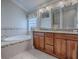 Luxurious bathroom with double vanities, a soaking tub with tile surround, and decorative accents at 2044 Larkwood Ct, The Villages, FL 32162