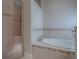 Elegant bathroom featuring a soaking tub with tile surround and a tiled shower with glass door at 2044 Larkwood Ct, The Villages, FL 32162