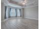 Spacious bedroom featuring tray ceiling, light gray walls, and light wood-look flooring at 2044 Larkwood Ct, The Villages, FL 32162