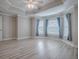 Spacious bedroom featuring tray ceiling, light gray walls, and light wood-look flooring at 2044 Larkwood Ct, The Villages, FL 32162