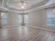 Bright bedroom features a decorative tray ceiling, neutral walls, and large windows with sheer curtains at 2044 Larkwood Ct, The Villages, FL 32162