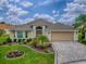 Beautiful single-story home featuring a pristine lawn, colorful flowerbeds, a paver driveway, and a two-car garage at 2044 Larkwood Ct, The Villages, FL 32162