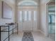 Inviting foyer with tile flooring, decorative glass door, and modern console table at 2044 Larkwood Ct, The Villages, FL 32162
