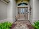 Elegant front door with decorative glass panels and transom window, complemented by lush greenery at 2044 Larkwood Ct, The Villages, FL 32162