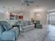 Spacious living room featuring a ceiling fan, plush rug, and seamless flow to the adjacent kitchen at 2044 Larkwood Ct, The Villages, FL 32162