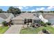 Well-manicured front yard features a paver driveway, lush landscaping, and a charming, inviting exterior at 2096 Callaway Dr, The Villages, FL 32162