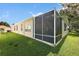 The exterior view shows a large screened-in porch extending from the house, surrounded by a well-kept lawn and blue skies at 2096 Callaway Dr, The Villages, FL 32162