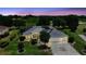 Aerial view shows home with solar panels, golf course views, and vibrant landscaping at dusk at 2125 Horizon Run, The Villages, FL 32162