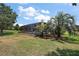 Backyard with a screened-in porch and pool, surrounded by lush landscaping and large palm trees at 2125 Horizon Run, The Villages, FL 32162