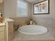 Soaking tub with decorative tile and window with plantation shutters at 2125 Horizon Run, The Villages, FL 32162
