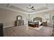 Serene main bedroom featuring a tray ceiling, wood-look floors, and a stylish dresser with a mirror at 2125 Horizon Run, The Villages, FL 32162