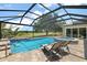 Sparkling pool and spa with a screened enclosure, lounge chairs and manicured landscaping at 2125 Horizon Run, The Villages, FL 32162