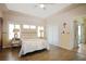 Cozy bedroom featuring wood floors, a tray ceiling, and bright natural lighting from multiple windows at 21646 Stirling Pass, Leesburg, FL 34748