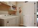 Clean laundry room featuring white washer and dryer, shelving, white walls, and tile flooring at 21646 Stirling Pass, Leesburg, FL 34748