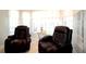 Bright living area featuring two black leather recliners situated near windows with white blinds and curtains at 21646 Stirling Pass, Leesburg, FL 34748