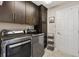 Well-equipped laundry room with dark wood cabinetry and modern washer and dryer units, offering convenience and style at 2325 Kenya St, The Villages, FL 32162
