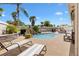 Beautiful pool area with rock waterfall feature, lush landscaping, stone pavers and lounge furniture at 2325 Kenya St, The Villages, FL 32162