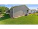 View of the home's vinyl siding, green grass, and minimal landscaping at 2348 Riley Rd, The Villages, FL 32162
