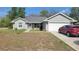 Charming one-story home with a well-manicured lawn, walkway and a red car in the driveway at 254 Locust Pass Dr, Ocala, FL 34472