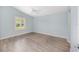 Comfortable bedroom with light blue walls, wood-look flooring, and large window with plantation shutters at 2564 Red Cedar Ln, The Villages, FL 32162