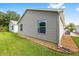 Exterior of a home with beige siding, green grass, and rock landscaping along the foundation at 2564 Red Cedar Ln, The Villages, FL 32162