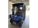 This attractive golf cart has a Marine logo, black interior, and custom wheels. It is stored inside the garage at 2564 Red Cedar Ln, The Villages, FL 32162