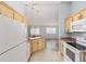 Galley kitchen featuring light wood cabinets, granite counters, and stainless steel appliances at 2564 Red Cedar Ln, The Villages, FL 32162