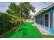 Inviting backyard featuring low-maintenance artificial turf, tropical palms, and lush landscaping around a blue mobile home at 2706 Vindale Rd, Tavares, FL 32778