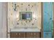 Bathroom showcasing floral wallpaper, a green framed mirror, and wooden cabinets under the sink at 2706 Vindale Rd, Tavares, FL 32778