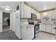 This kitchen features white cabinets and appliances, a decorative backsplash, with an opening to an adjacent hallway at 2706 Vindale Rd, Tavares, FL 32778