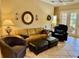 Inviting living room featuring a tan leather couch, chair, ottomans, and a ceiling fan at 3083 Pinnacle Ct, Clermont, FL 34711