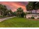 Westgate community entrance with a landscaped median, palm trees, and an orange sky backdrop at 3141 Brighton Rd, Eustis, FL 32726