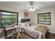 Cozy bedroom with natural light from two windows, a decorative ceiling fan and a writing desk at 33637 E Lake Joanna Dr, Eustis, FL 32736