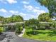 Inviting single-story home with a covered carport and lush front yard landscaping on a sunny day at 33637 E Lake Joanna Dr, Eustis, FL 32736