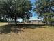 Backyard view featuring mature trees, a black metal fence, and partial view of the home's exterior at 33818 Venice Ln, Sorrento, FL 32776